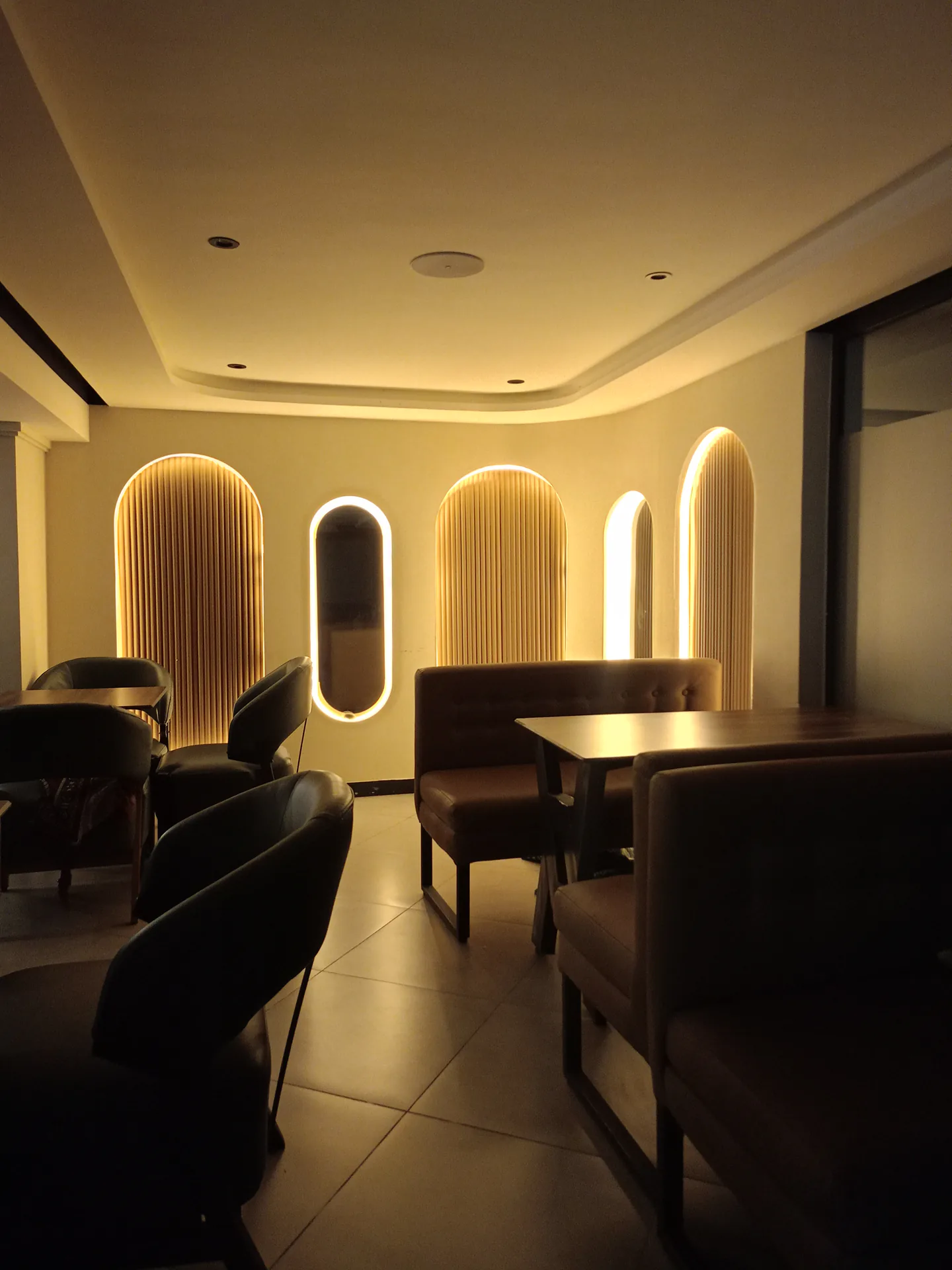 Salon chaleureux avec arches éclairées et banquettes chez LOLITA